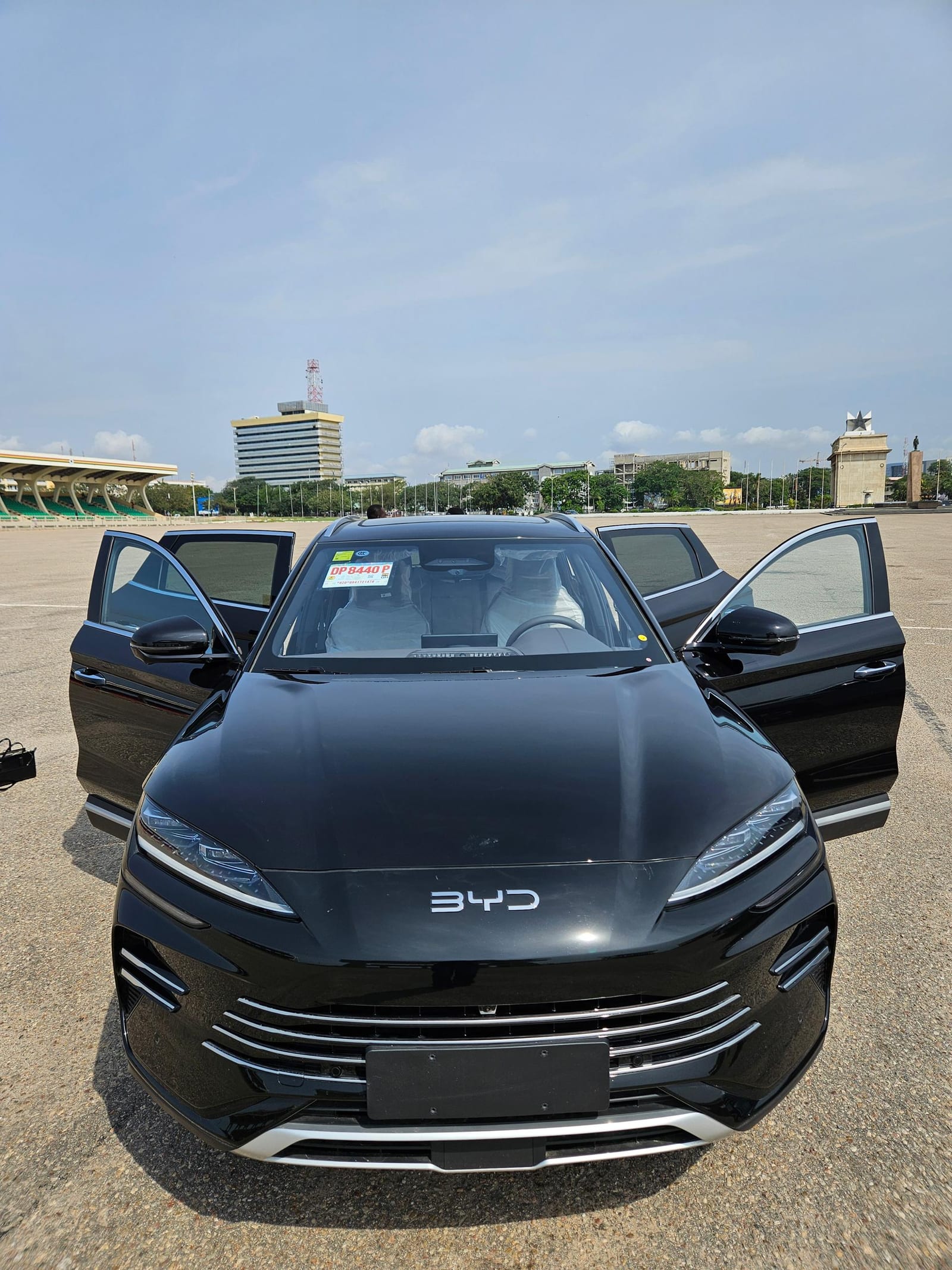 Black 2025 BYD Song Plus with both front doors open at Independence Square Accra, Ghana — Transparent Rentals fleet vehicle with cream leather interior visible, available for airport transfers and full-day car hire